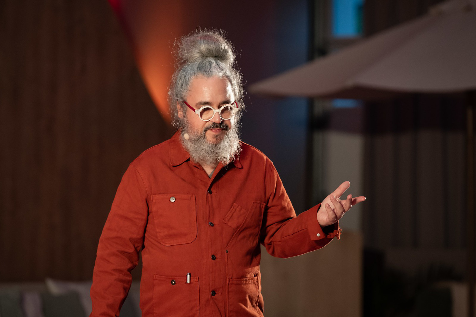 Close-up of a speaker in an orange jacket gesturing on the TEDxMitte stage