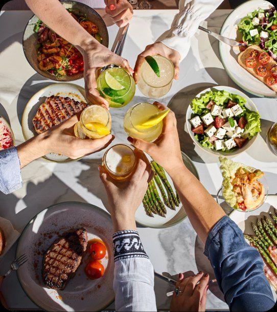 Colleagues toasting over a summer table full of grilled dishes and salads