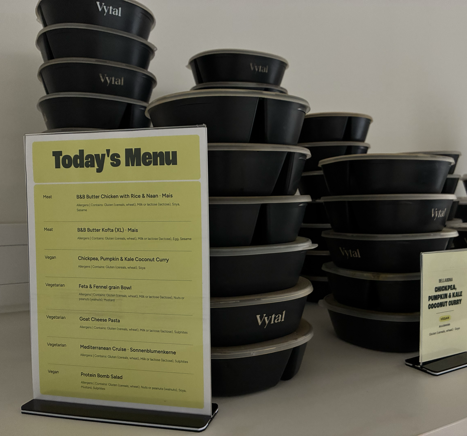 Stacked lunch boxes with labels for each dish on the buffet table