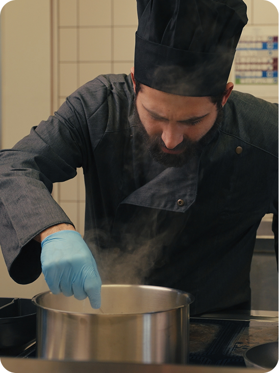 Chef stirring a steaming pot in the kitchen