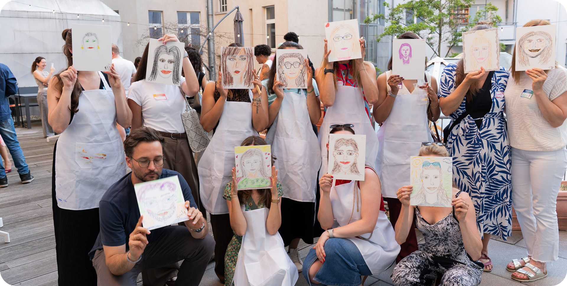 The team holding up self-portrait drawings from a workshop
