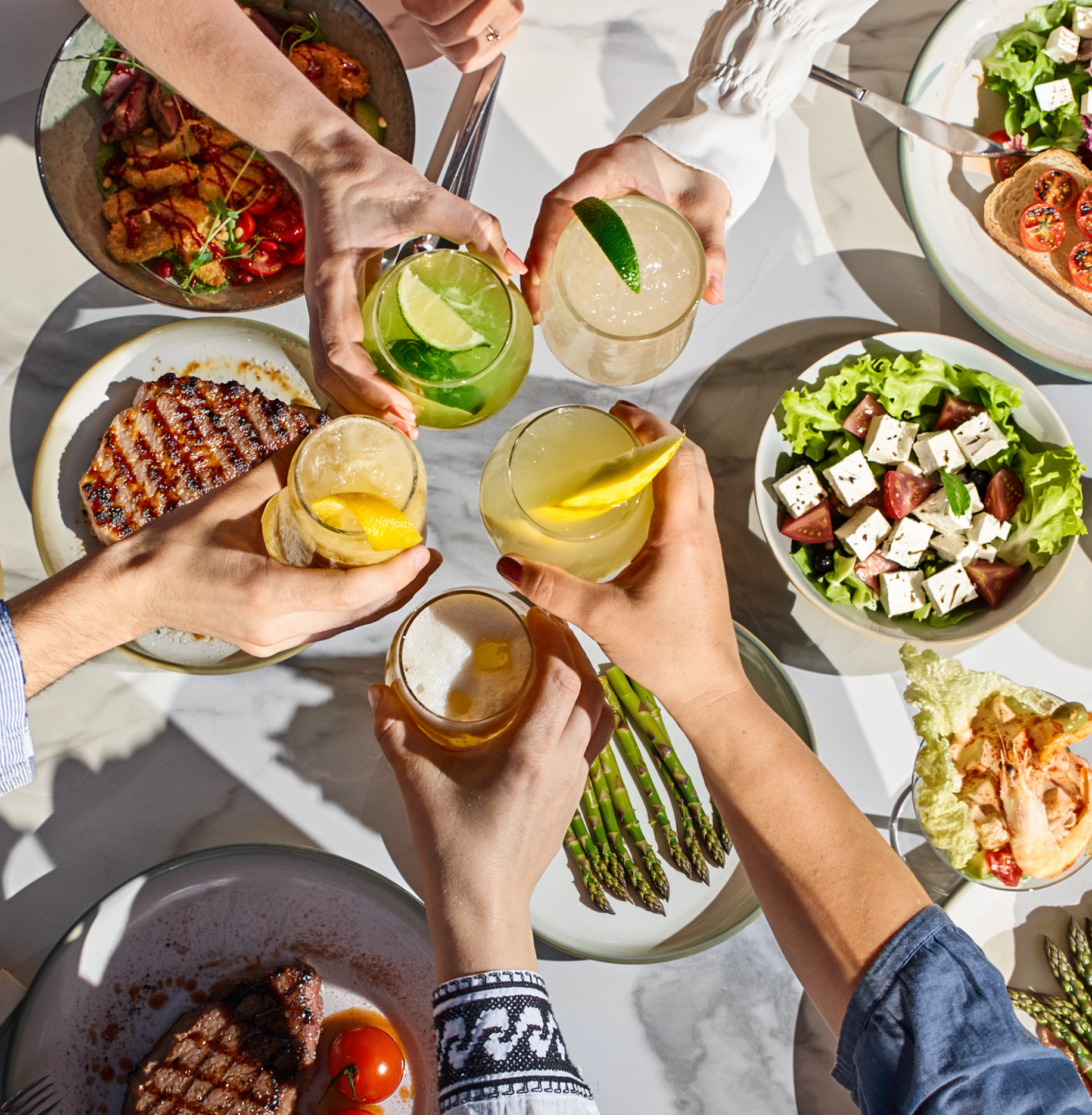 Colleagues toasting over a summer table full of grilled dishes and salads