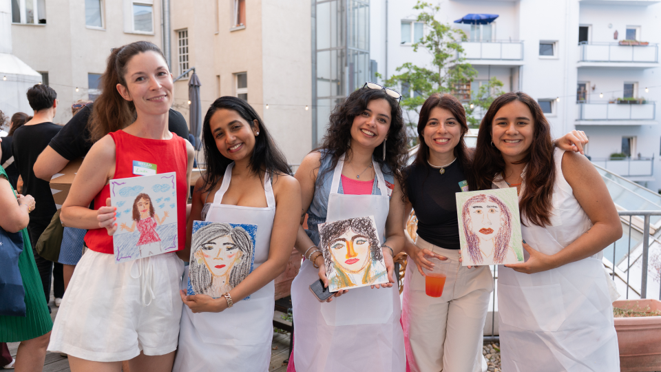 Guests holding up self-portrait drawings from a workshop