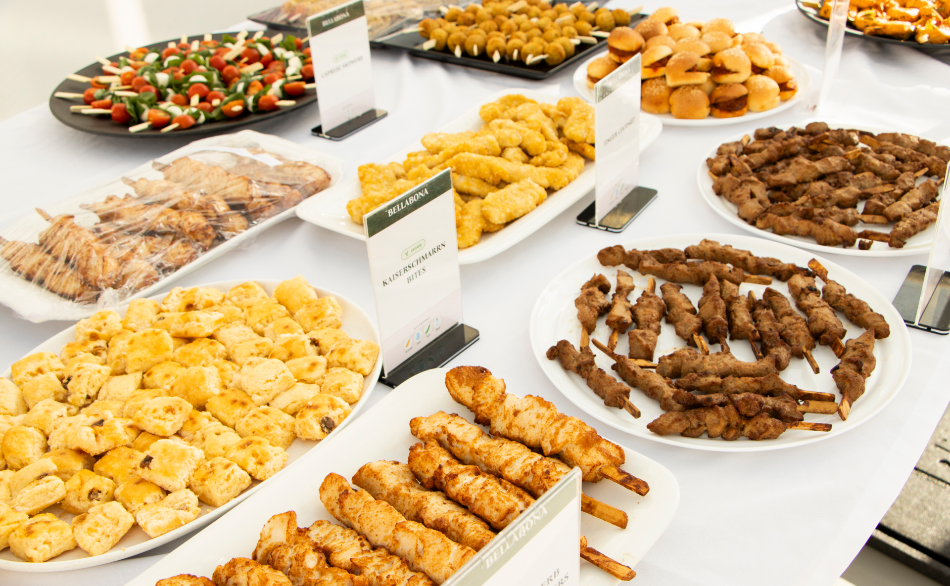 Catering-Buffet von oben mit Platten voller Gebäck, Gemüsespießen, Quiches und Brezeln