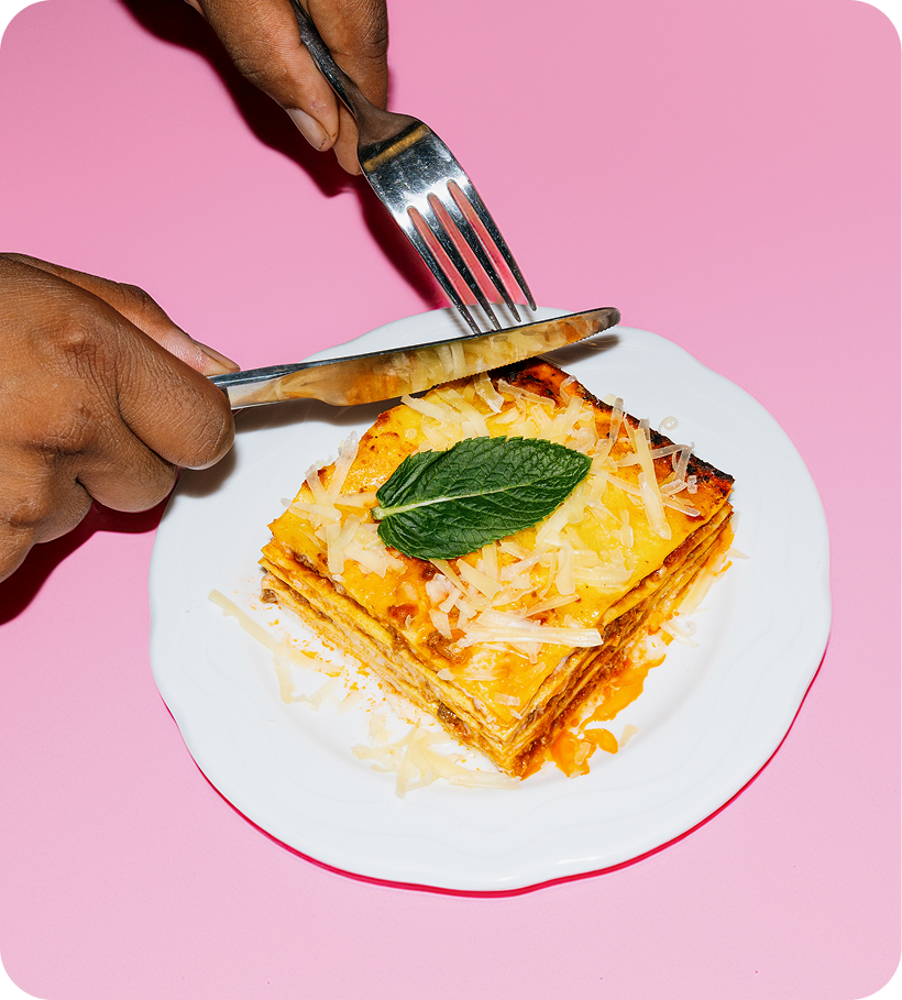 Freshly sliced lasagna plated and garnished with mint