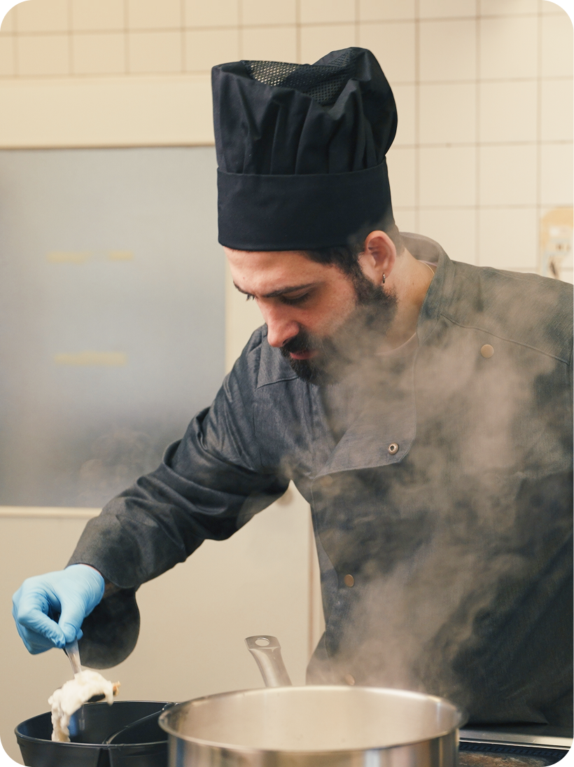 Chef stirring a steaming pot in the kitchen