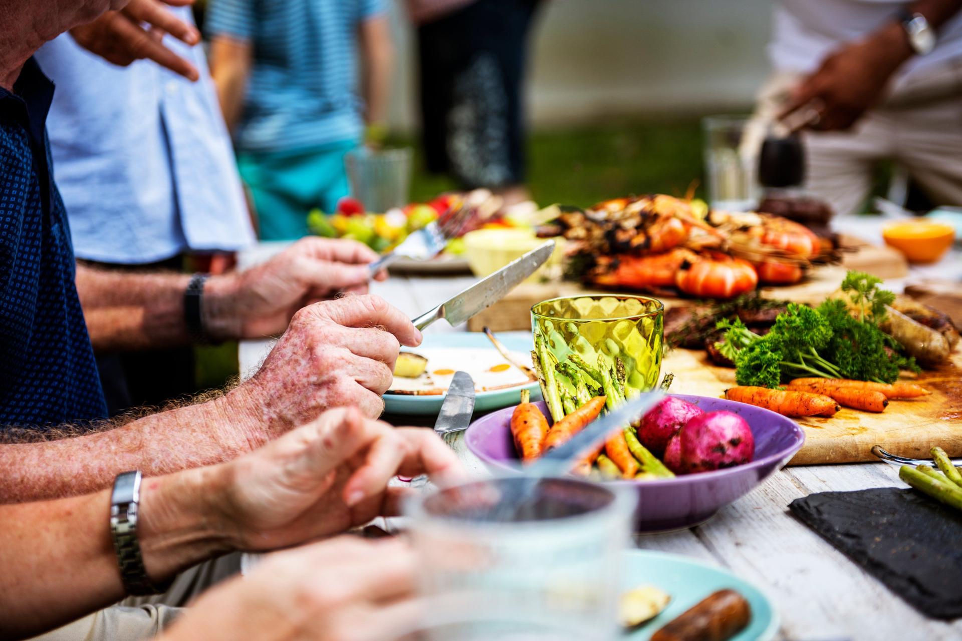 Colleagues sharing a summer BBQ spread with grilled vegetables and fresh salads