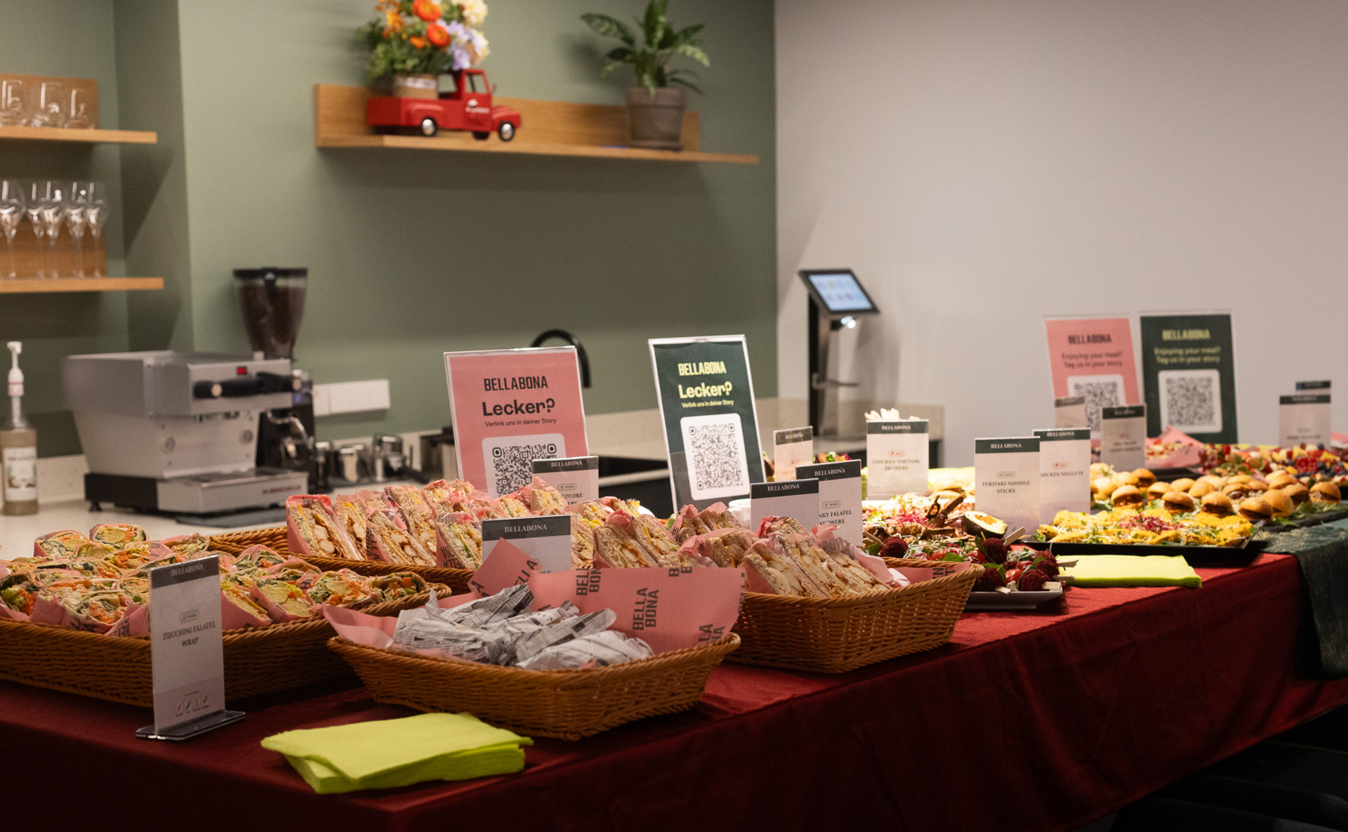 Catering-Buffet mit gekennzeichneten Gerichten, Broten und Gebäck auf einem rot gedeckten Tisch